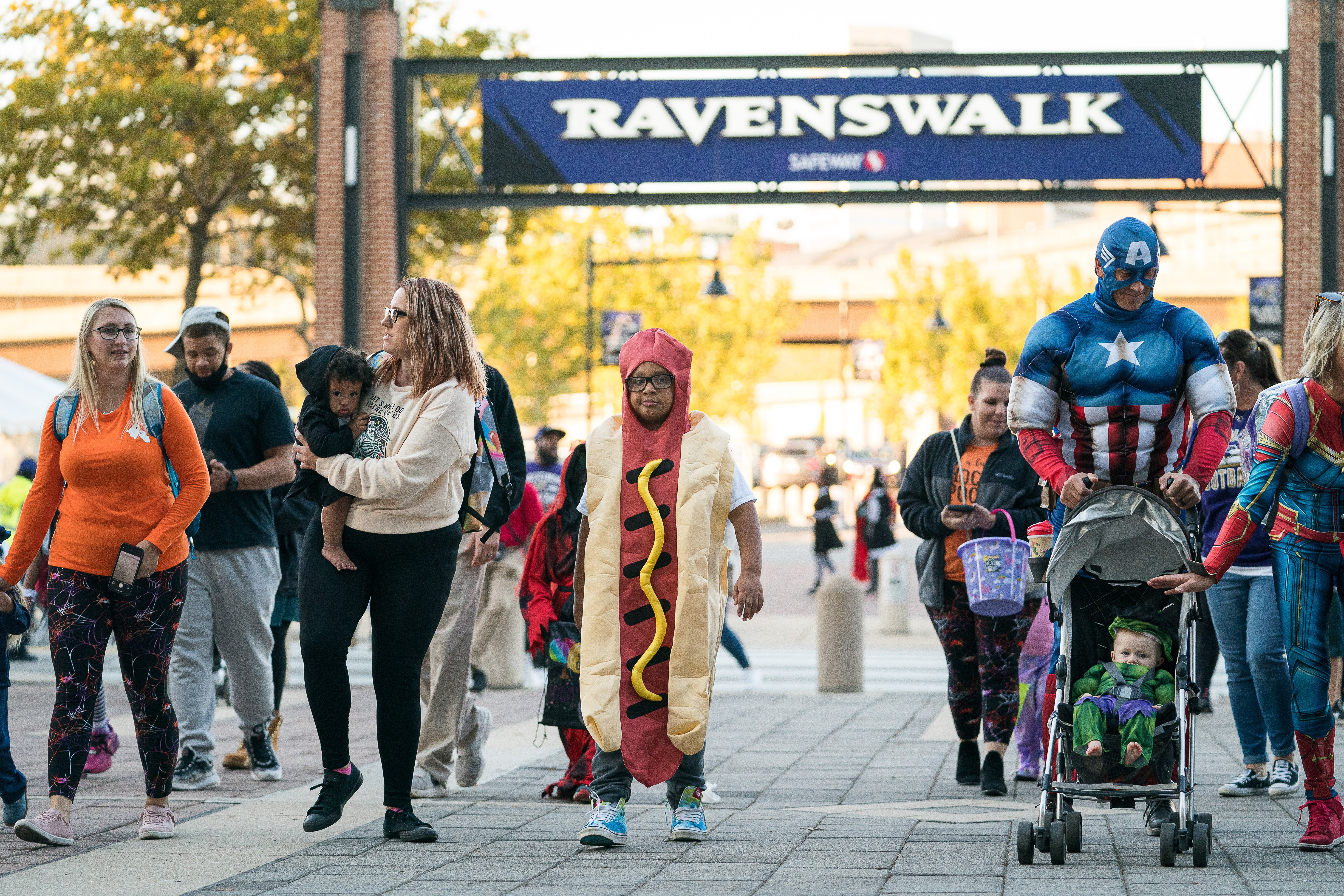 Kids trick or treating in costumes walking under the Ravenswalk sign