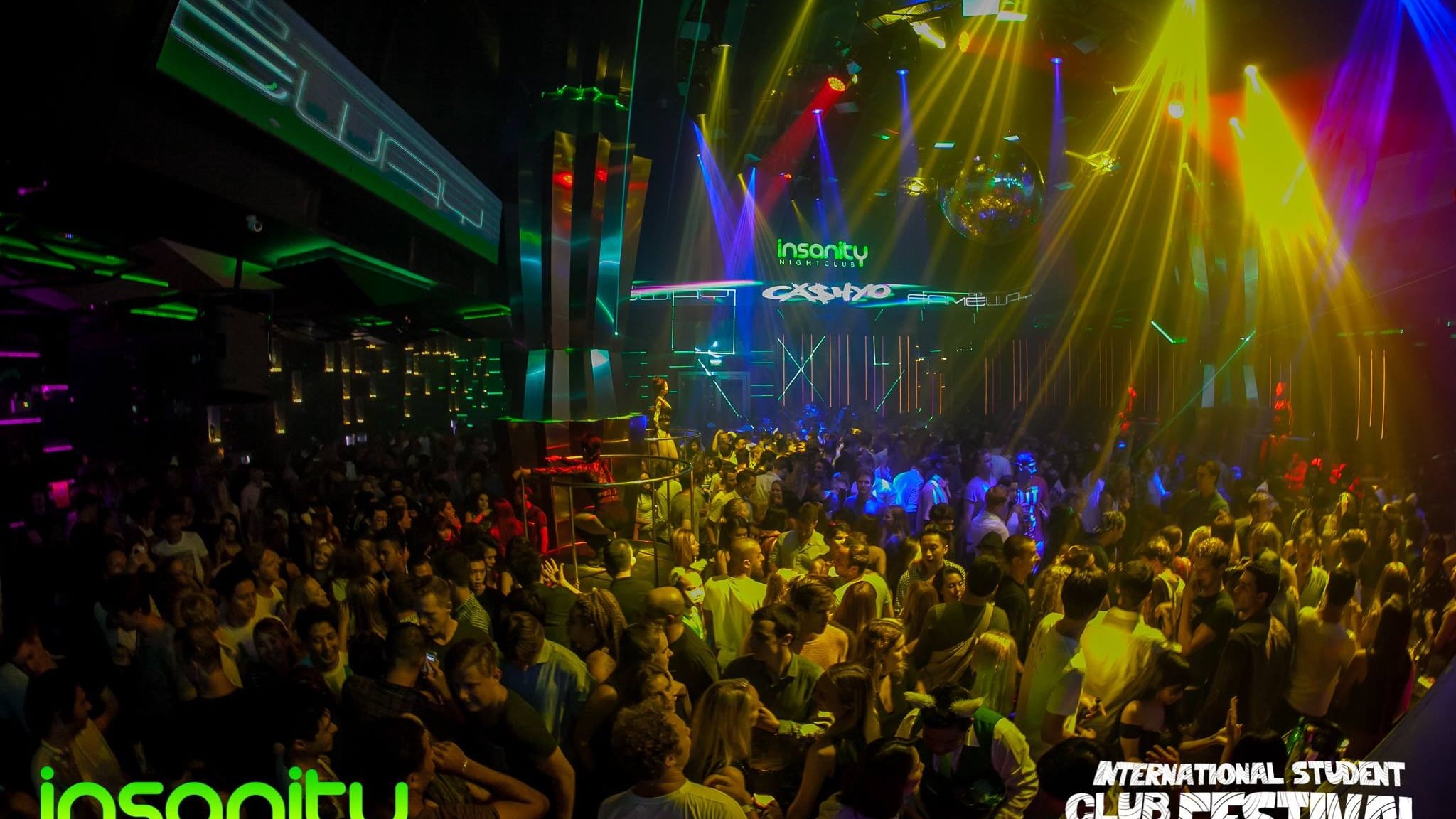 Crowd under yellow light beams at Insanity