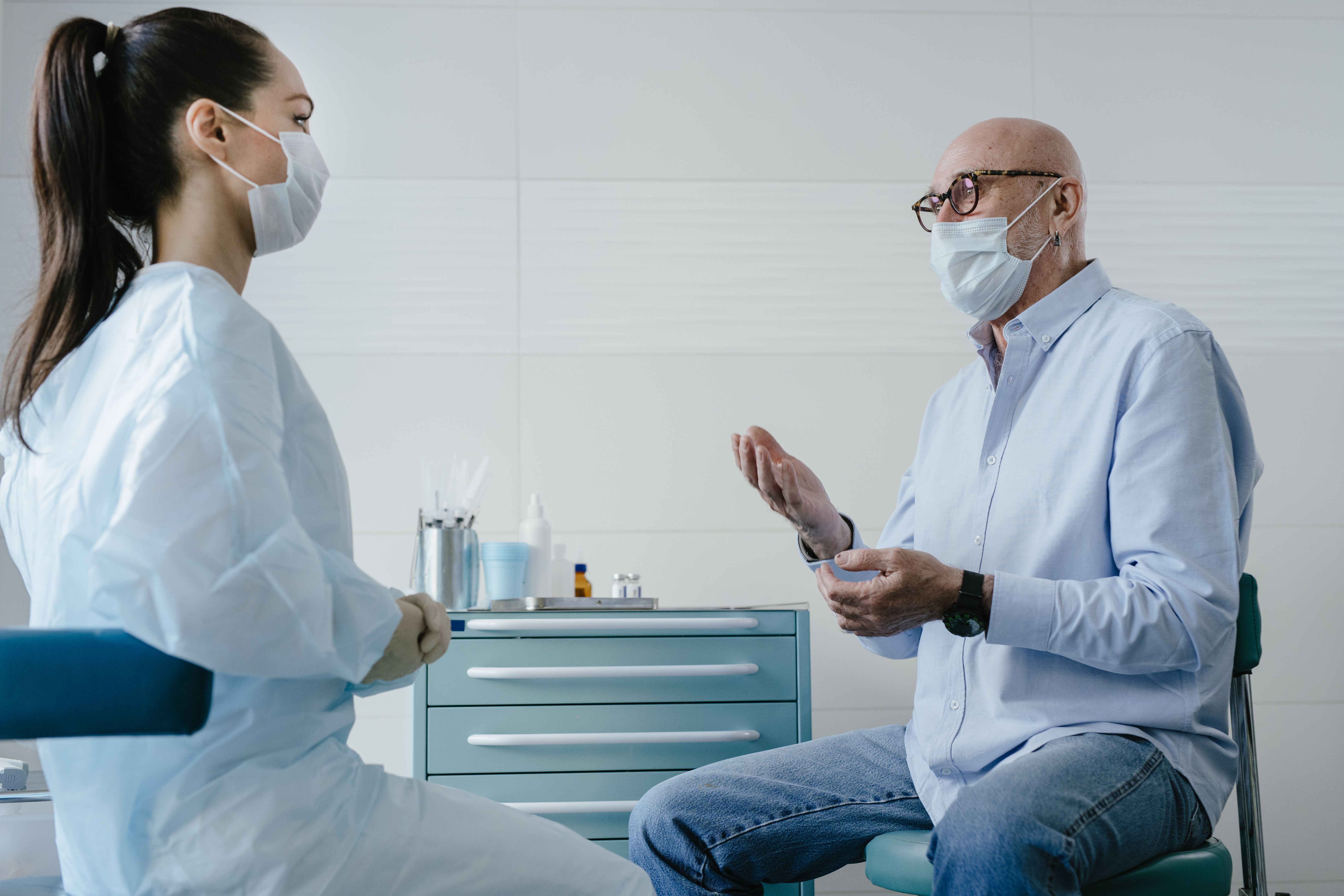 A clinician and an older patient reviewing medication together in a clinic, an unlabeled bottle on the counter