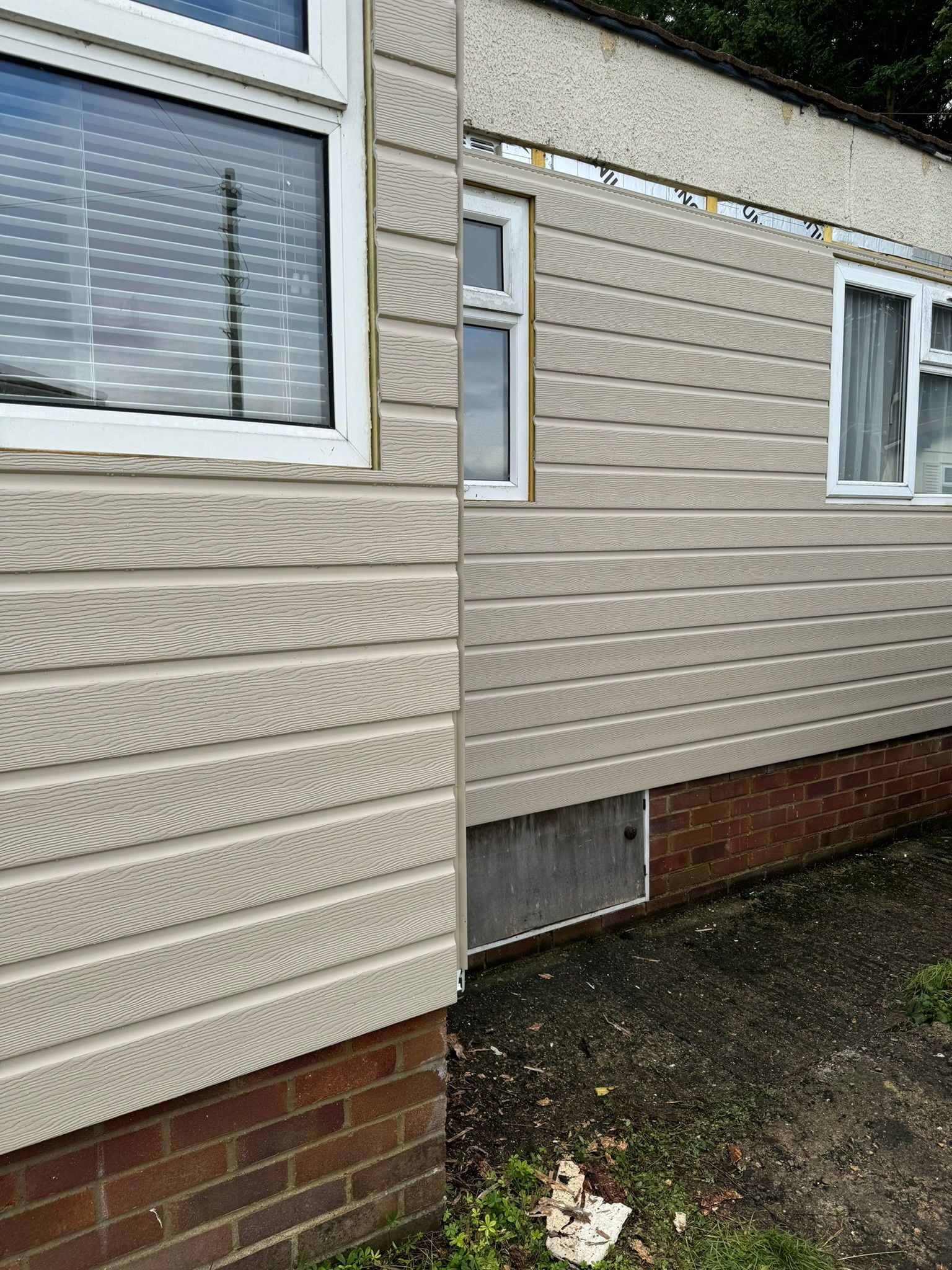 Side view of completed cream cladding installation on park home with multiple windows