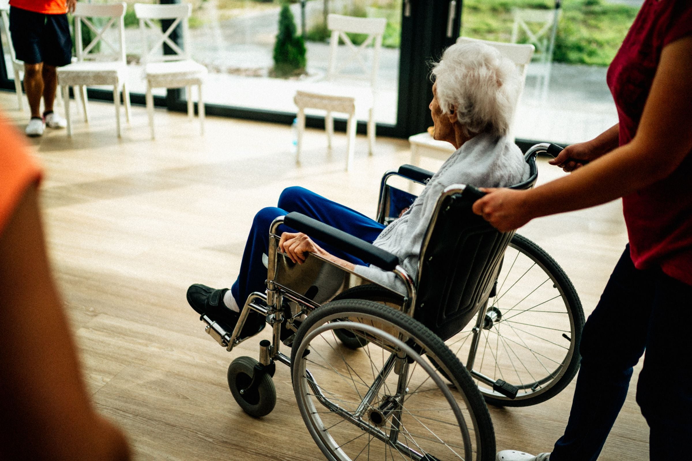 Carer sitting with an older resident in a bright aged care home