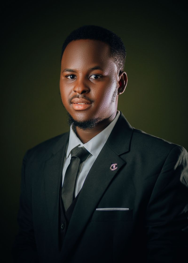 A confident young Black professional man in his early 30s in a dark suit, conveying a sharp and trustworthy advocate presence