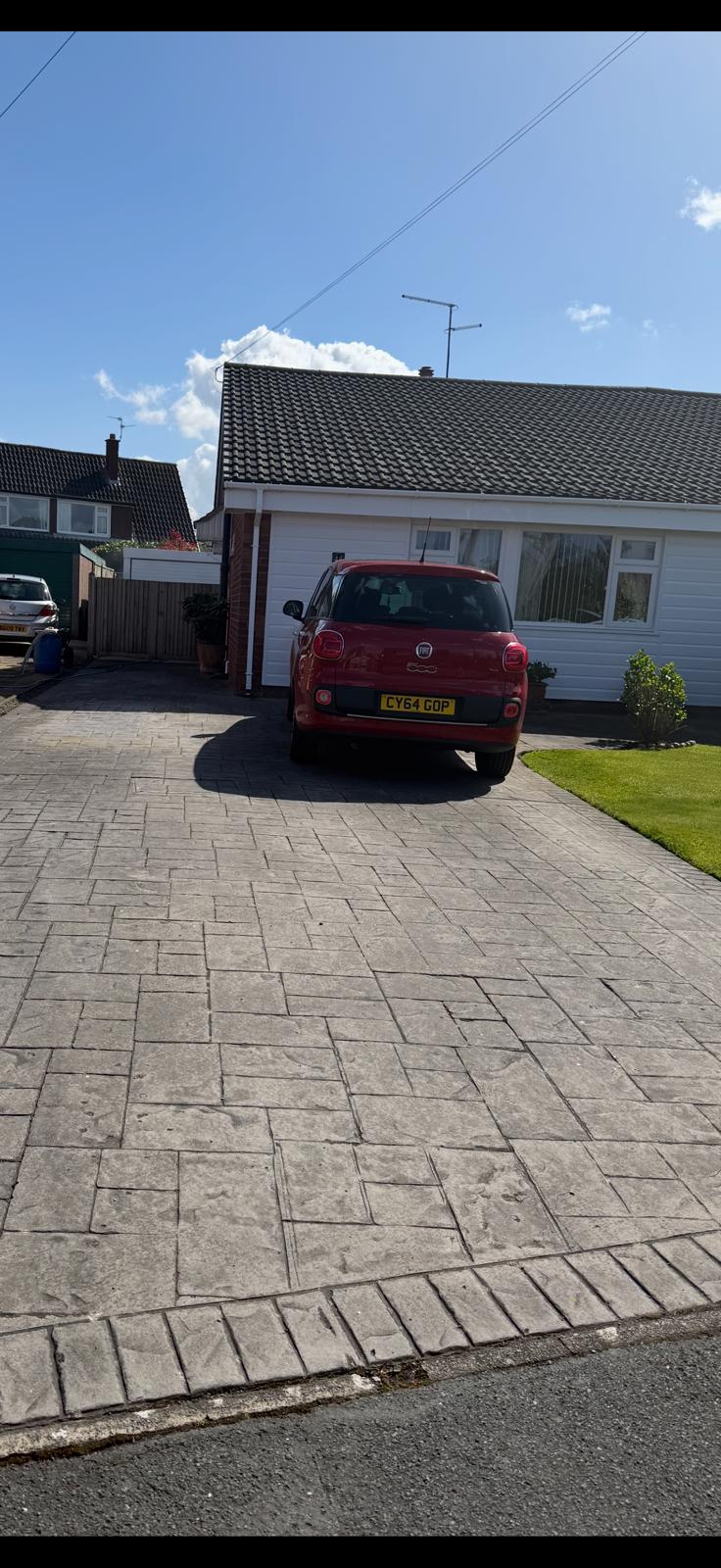Freshly cleaned stamped concrete driveway with red car parked