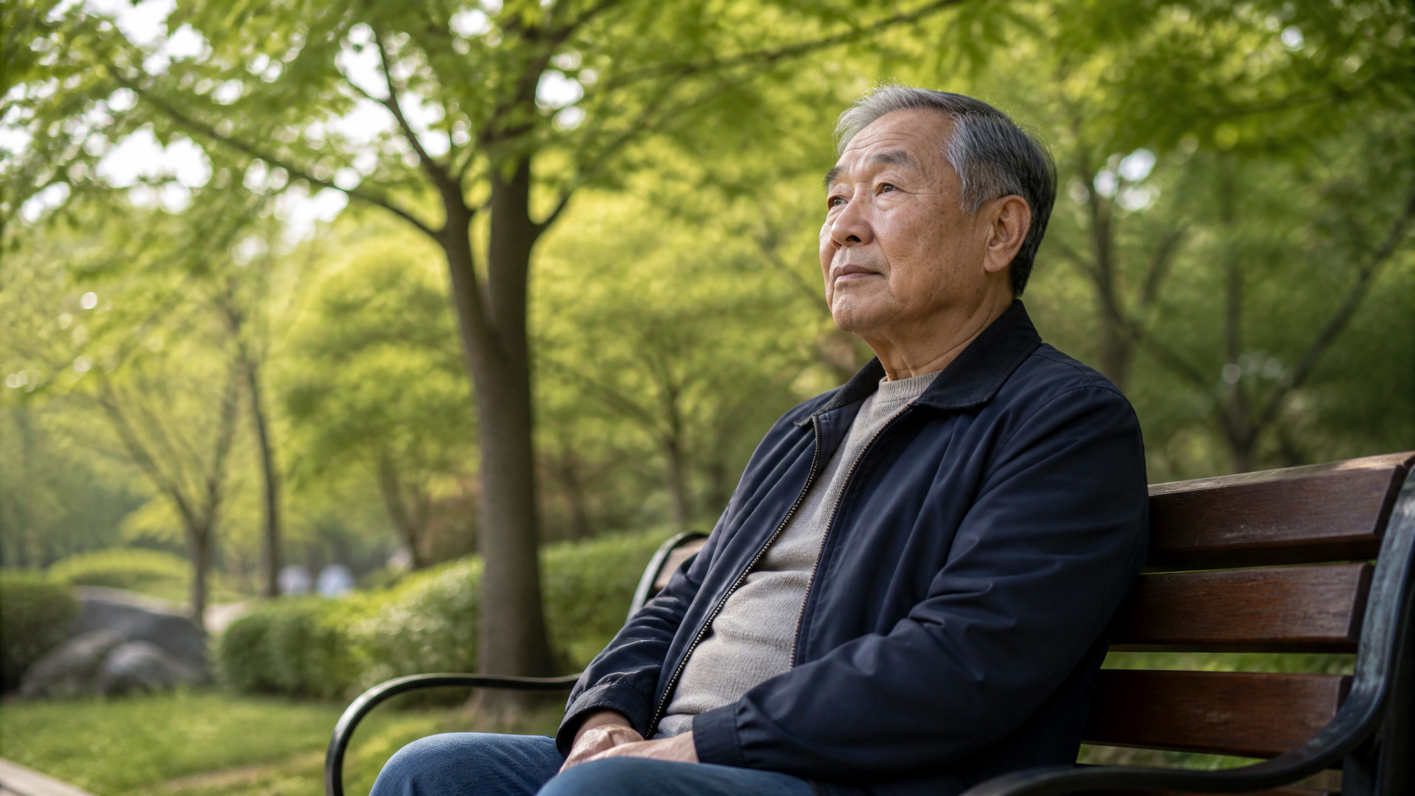 East Asian male veteran sitting peacefully on a park bench in quiet contemplation