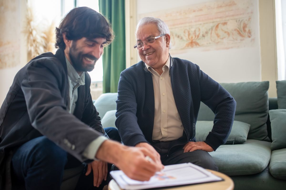 Two men sitting at a desk in a small office discussing the occupational and functional impact of a sleep disorder during a vocational assessment