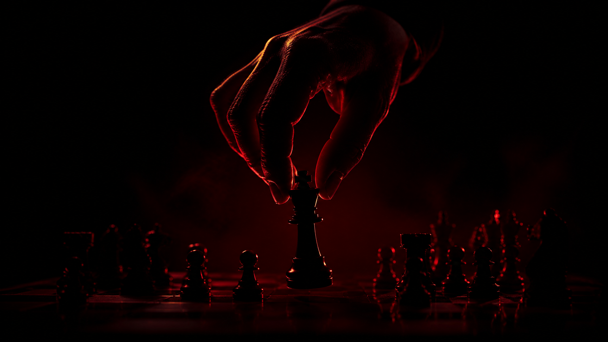 A hand in shadow moving a chess piece