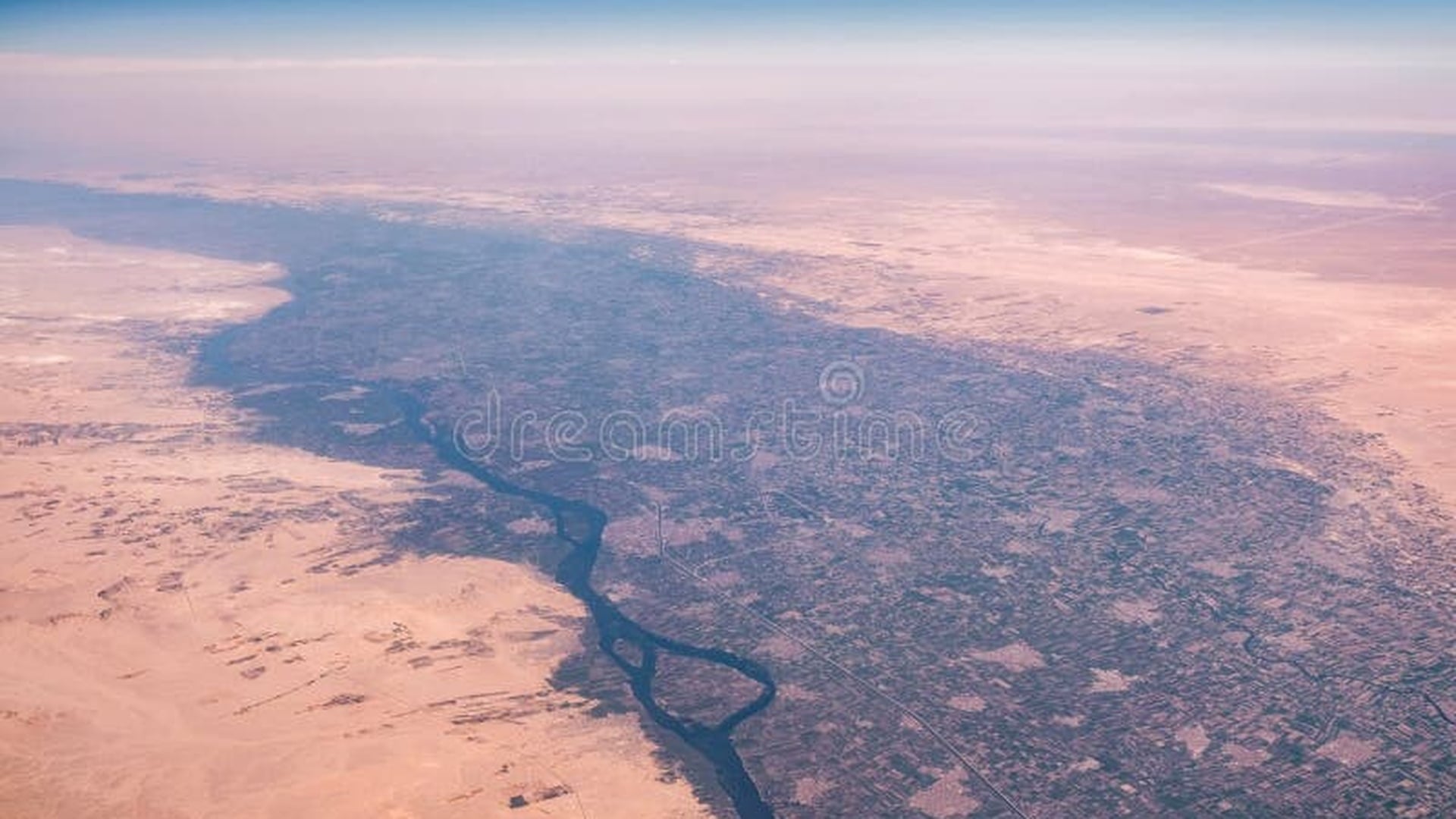 Aerial view of the Nile River flowing through green agricultural land surrounded by the Sahara desert