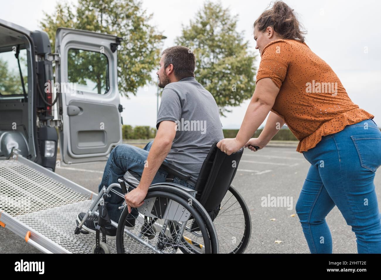 Caregiver and wheelchair user smiling near accessible vehicle