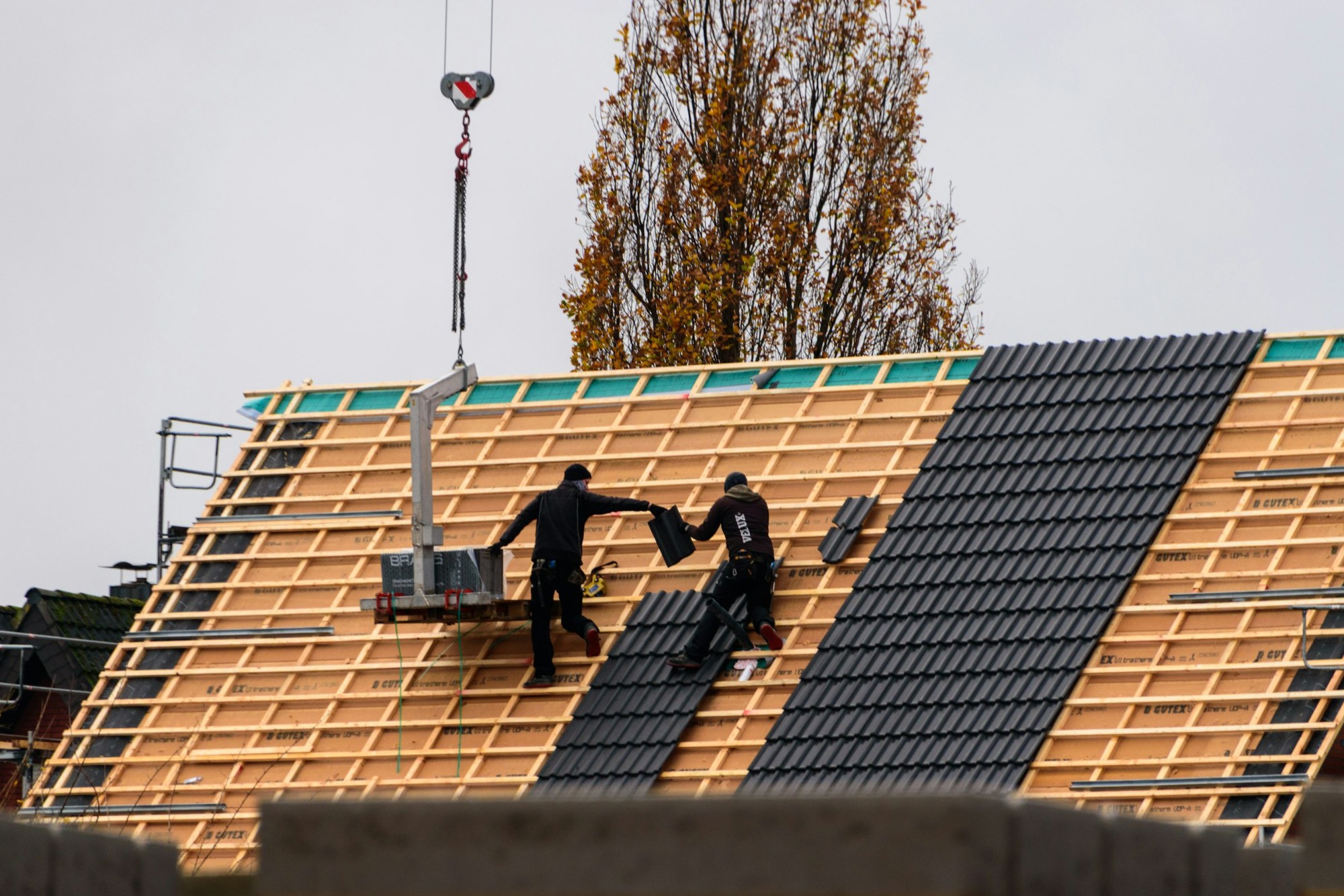 Roofers laying new tiles over fresh battens