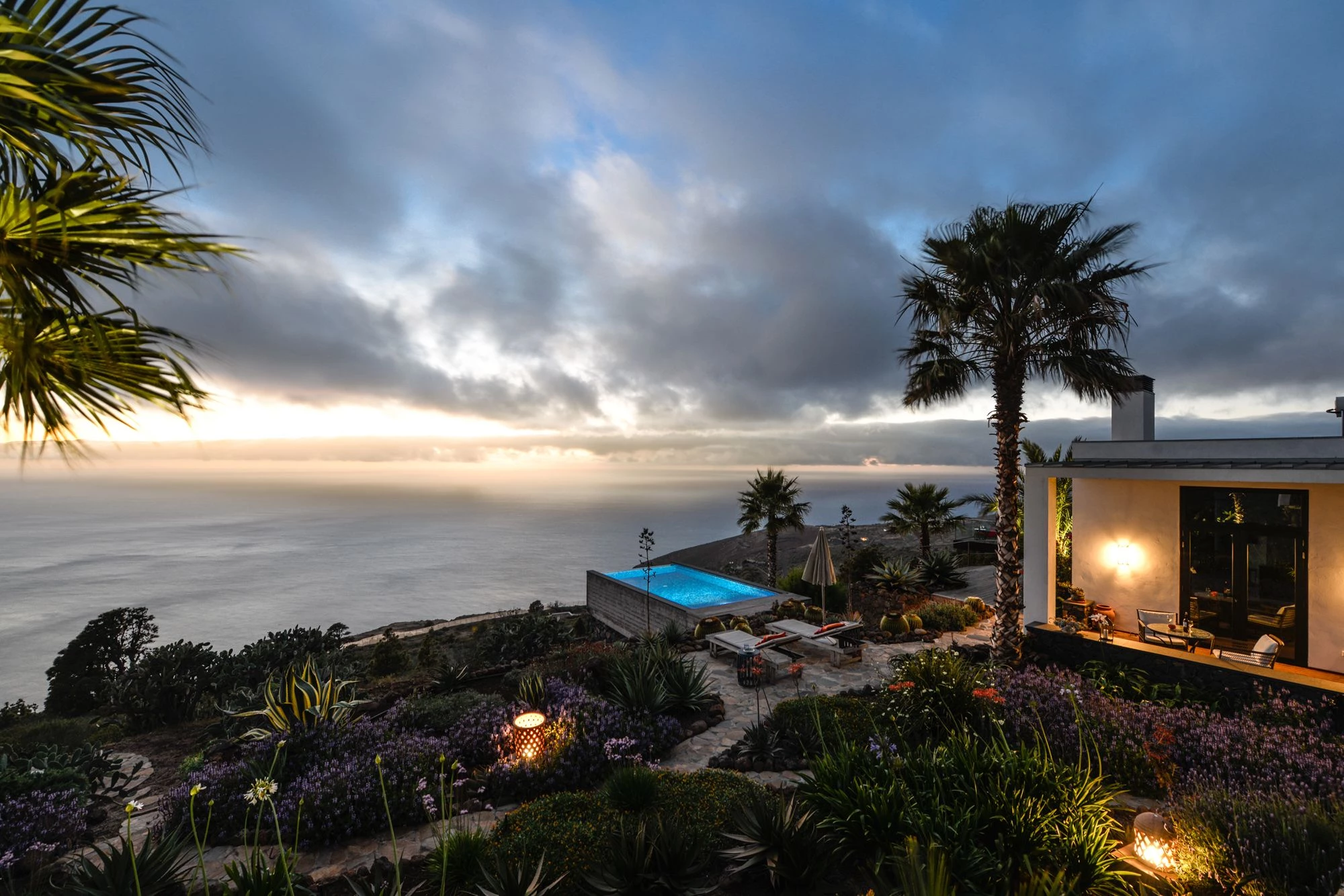 Villa at dusk with illuminated infinity pool and ocean view