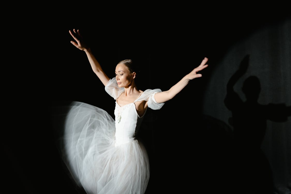Ballerina performing under spotlight with dramatic theatrical lighting