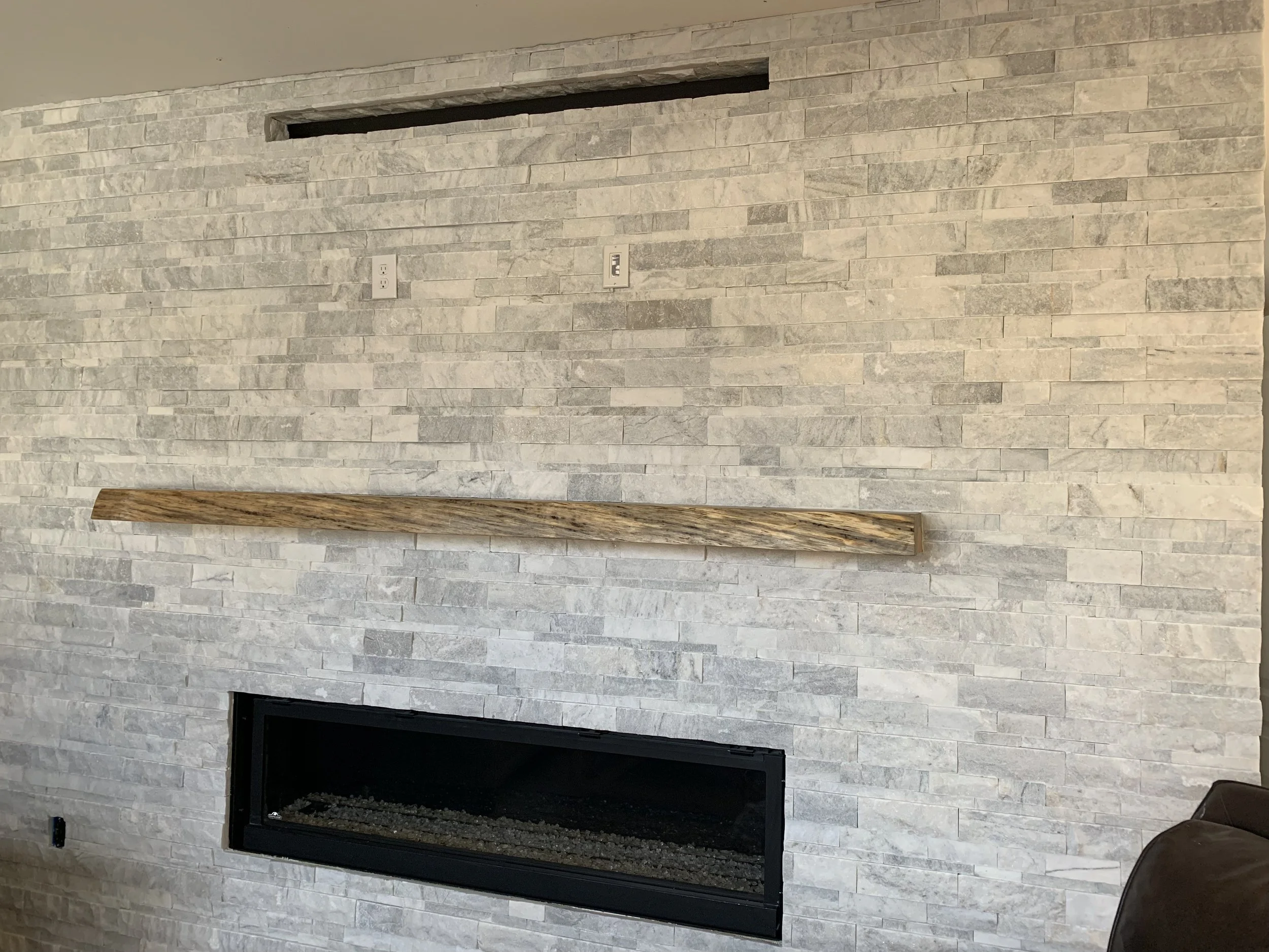 Modern living room fireplace with black frame set into white textured stone wall