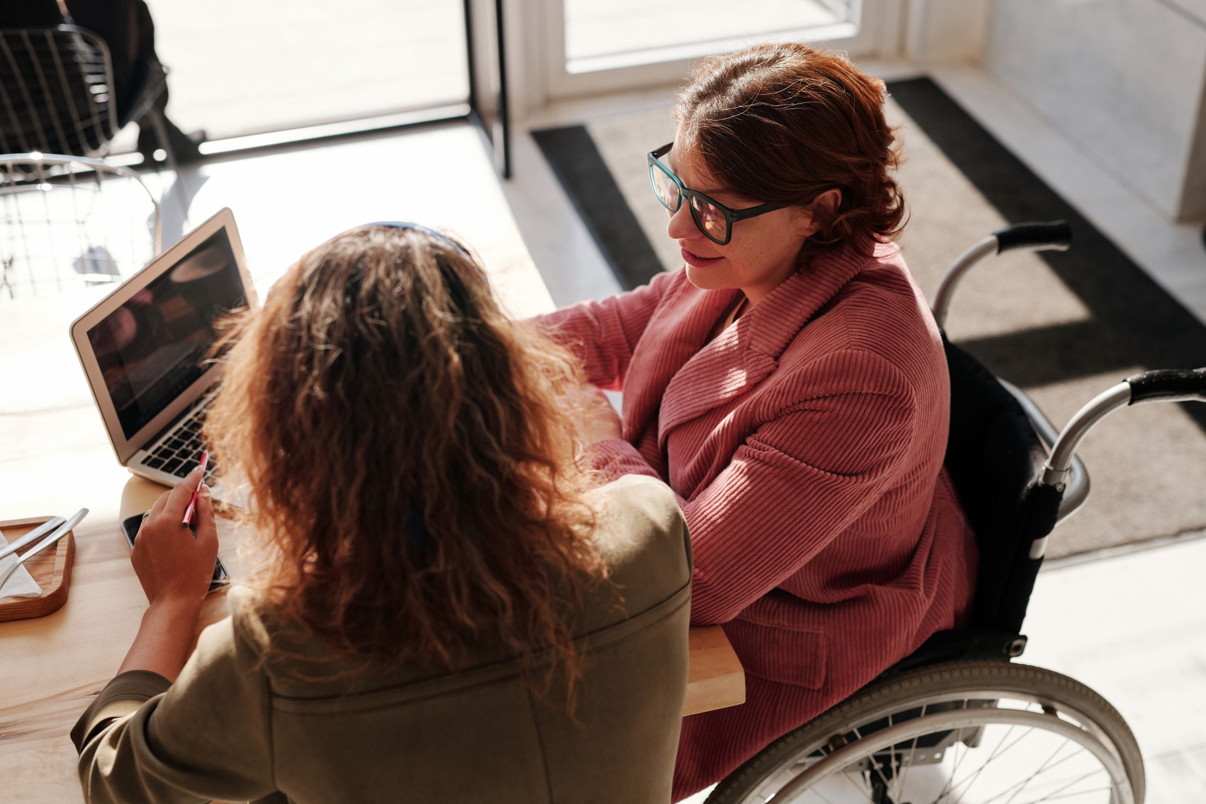 Support worker helping an NDIS participant in a wheelchair with a laptop