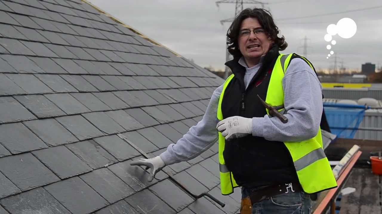 Roofer installing slate tiles on roof