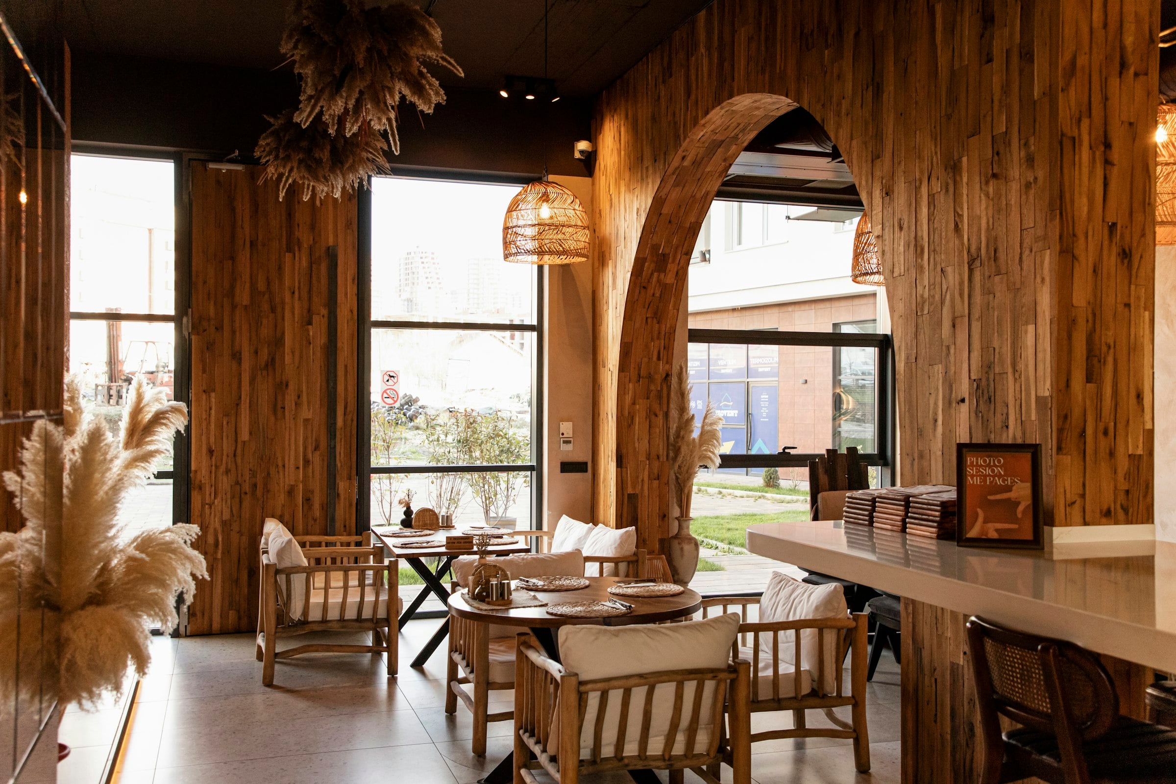 Salle lumineuse d'un restaurant indépendant, tables en bois et grandes fenêtres