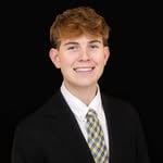 Formal headshot of Landon against a dark background.