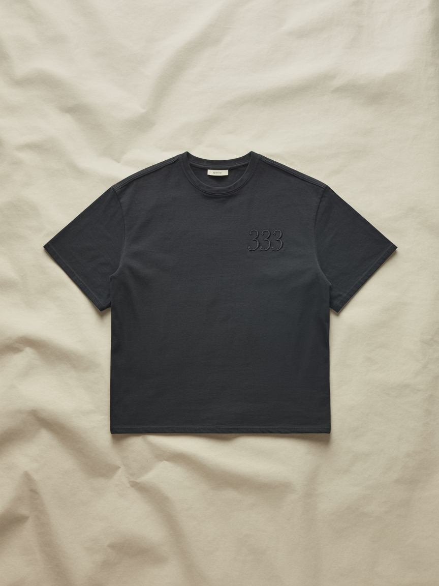 Pyramidion 333 Intuition Signal Tee in obsidian black, laid flat on a cream background.
