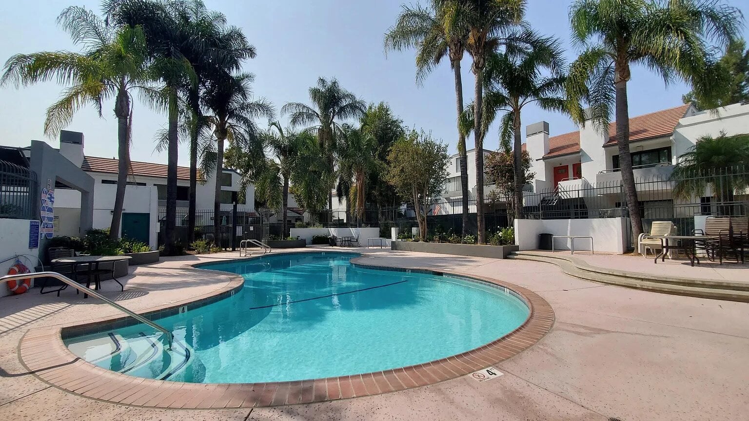 Community swimming pool surrounded by palm trees