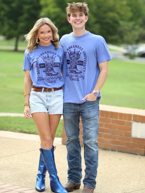 Landon standing with another adult in matching campus-themed shirts.