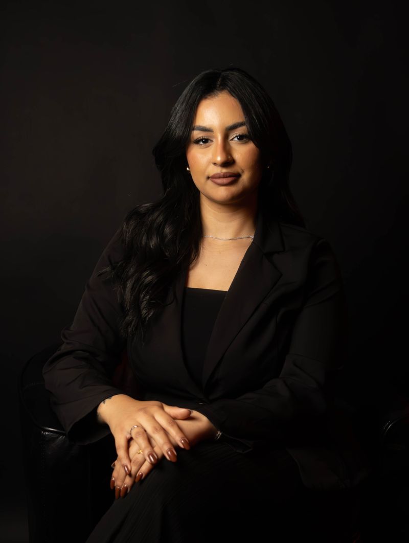 A professional woman in her 30s in a dark blazer seated confidently, conveying a calm and trustworthy advocate presence