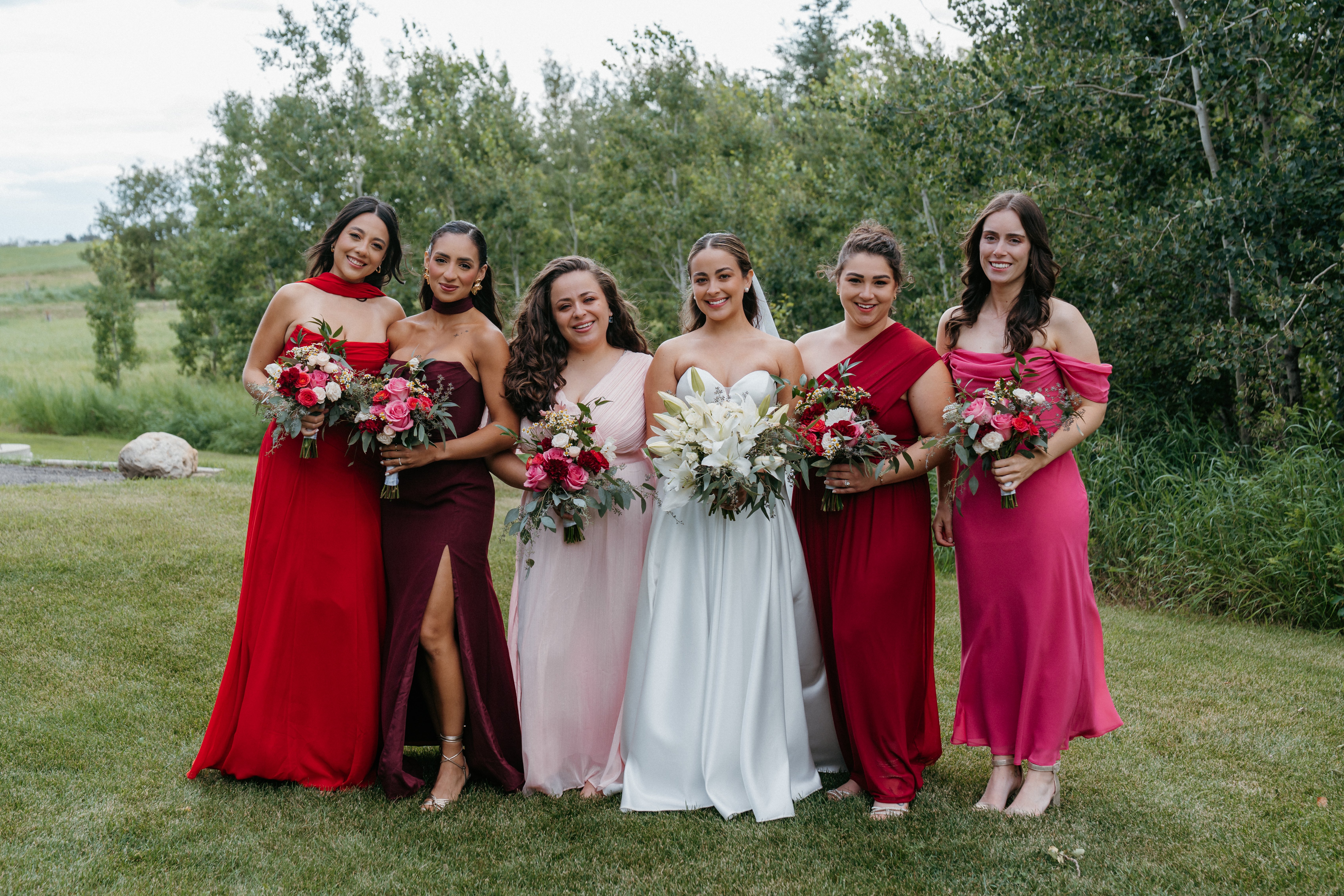 Bridal party with coordinated red and pink bouquets