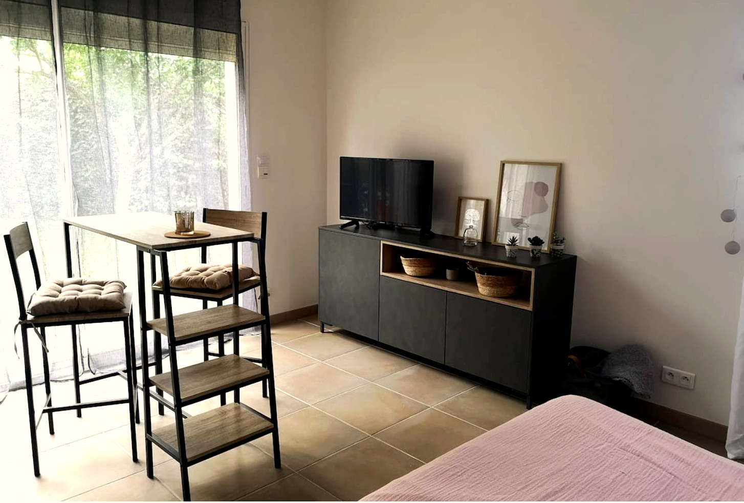 Coin salon du studio avec meuble TV et tabourets hauts