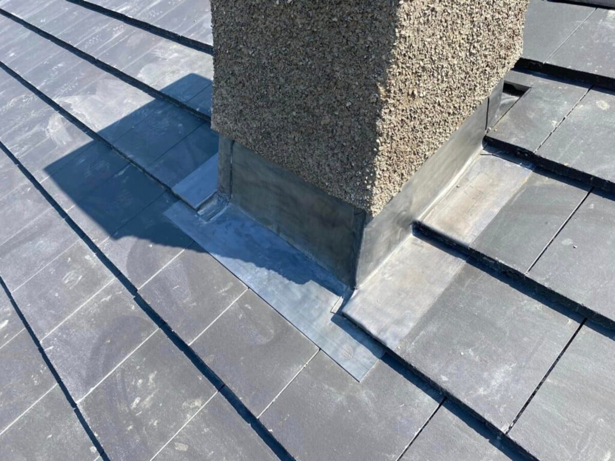 Lead flashing installation around a chimney base on a tiled roof