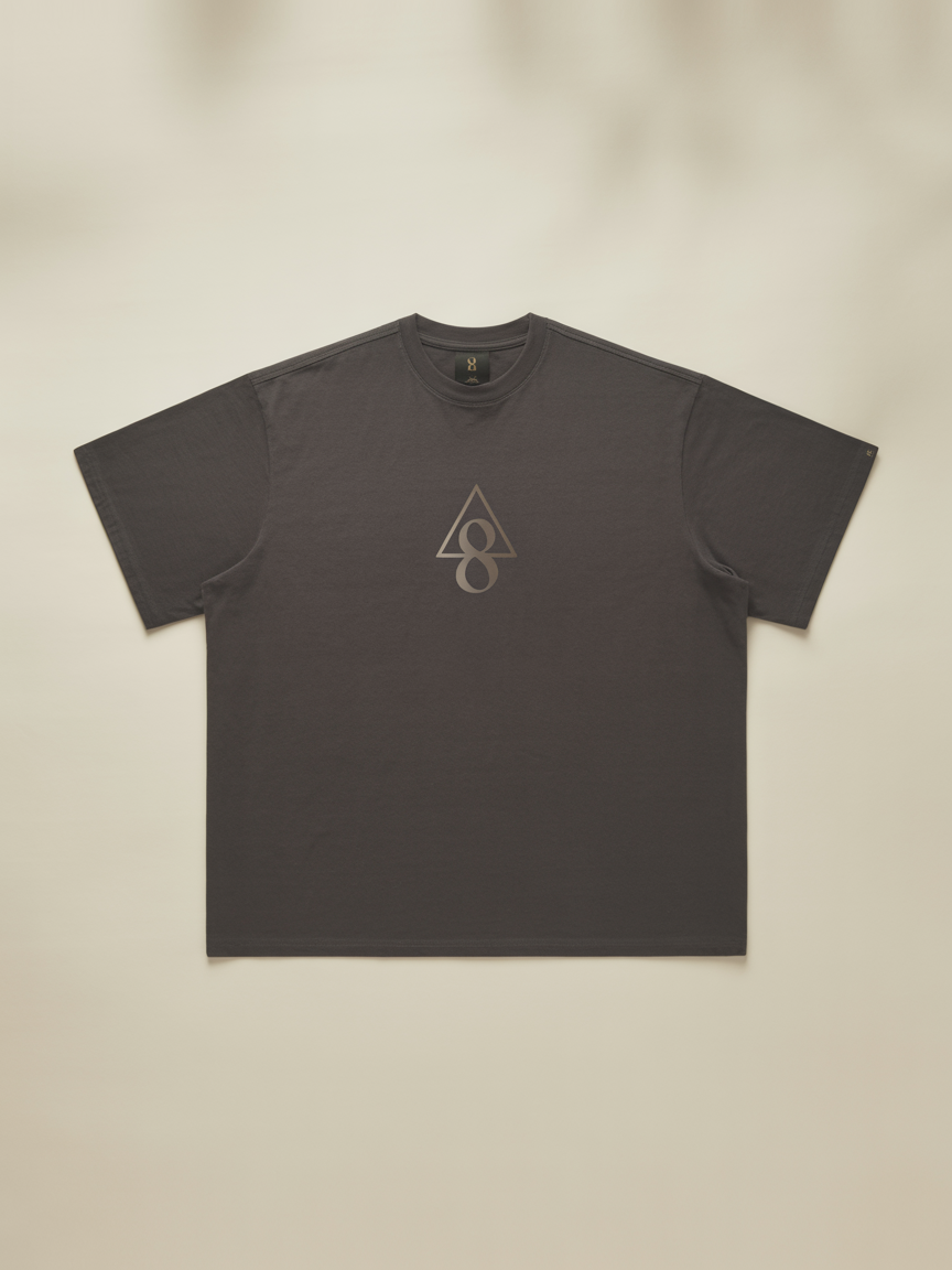 Pyramidion 8th Gate Tee in charcoal, laid flat on a cream background with a minimal pyramidion glyph.