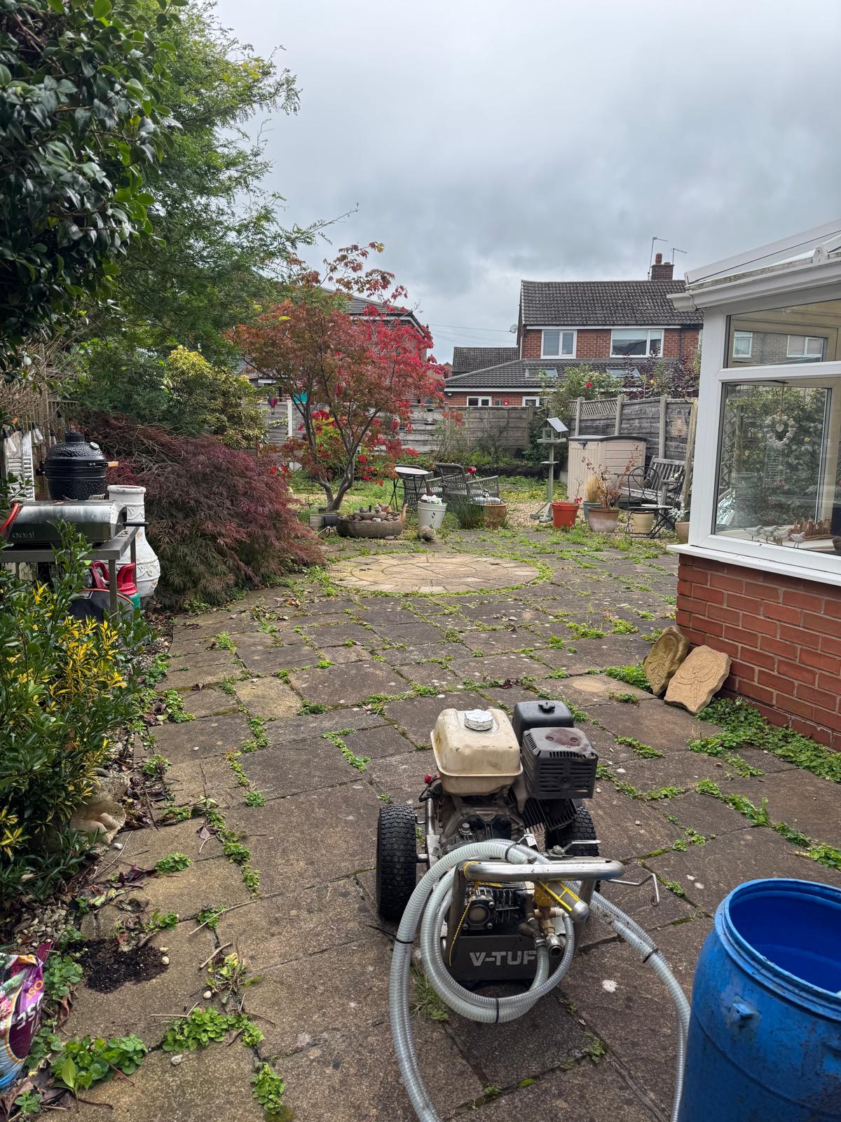 Back patio before cleaning - V-TUF washer set up, weeds between slabs