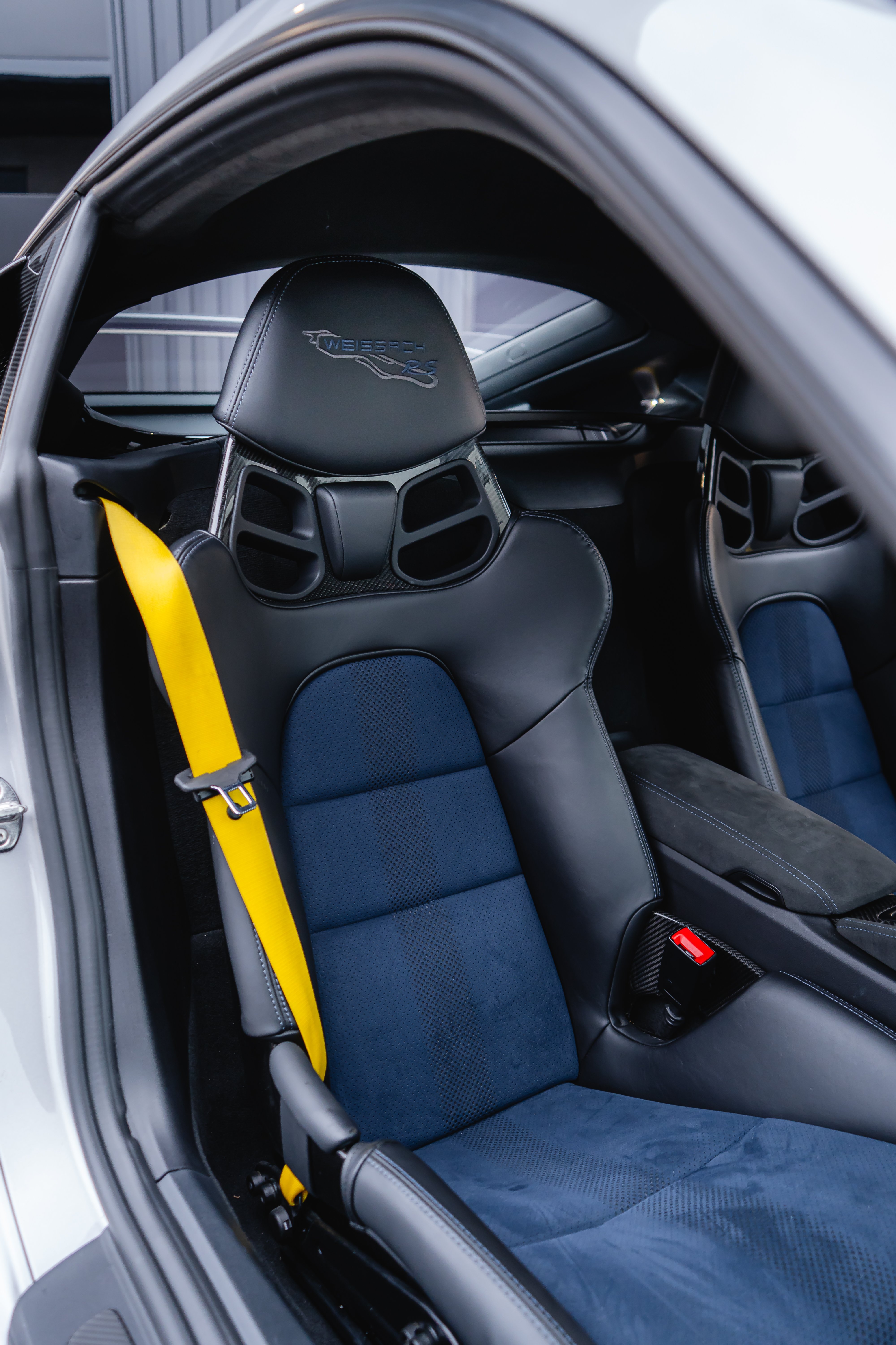 Door panel with carbon fiber trim, deep sea blue stitching, and yellow door pull