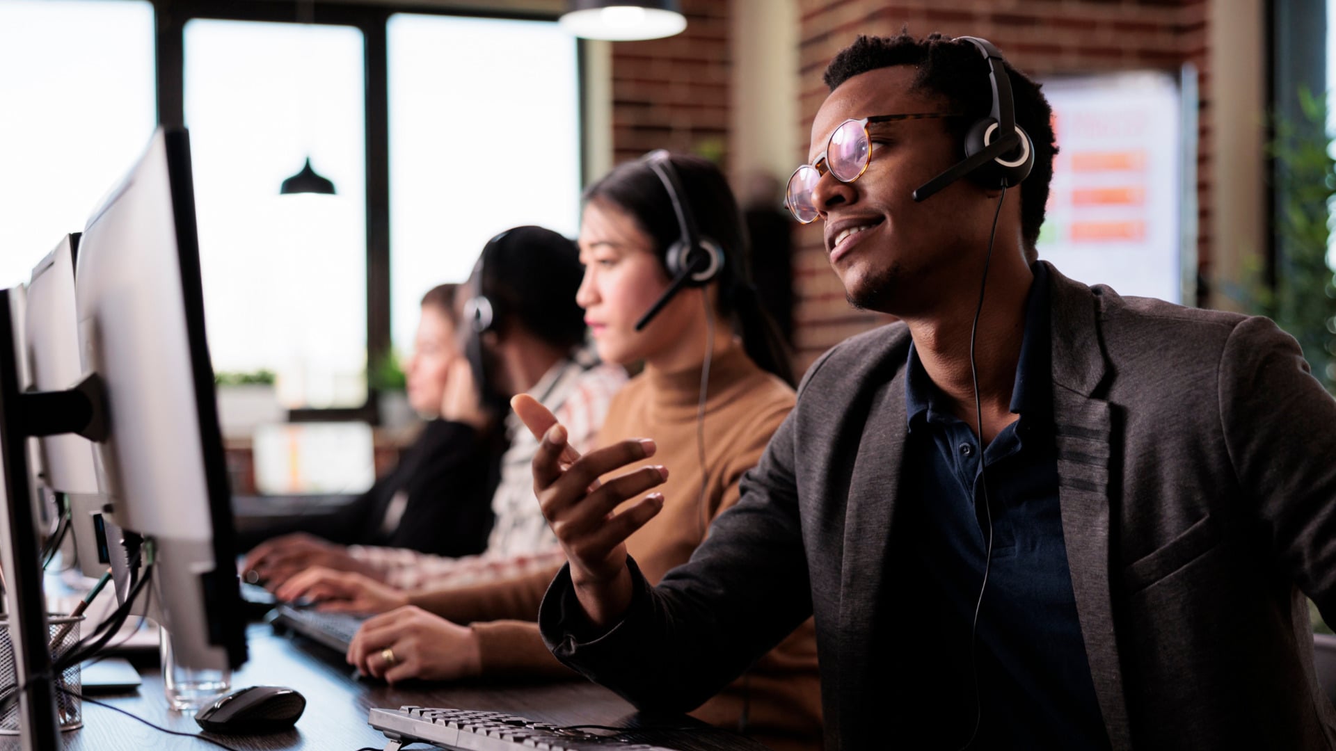Customer support team with headsets and monitors in modern call center