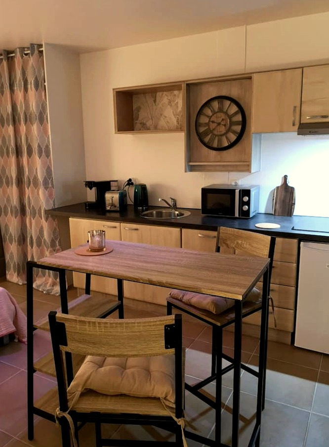 Cuisine équipée avec plan de travail noir et horloge ancienne