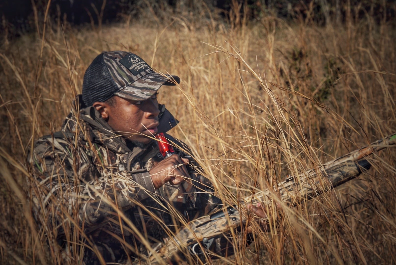Joshua Carney concealed in golden tall grass with rifle