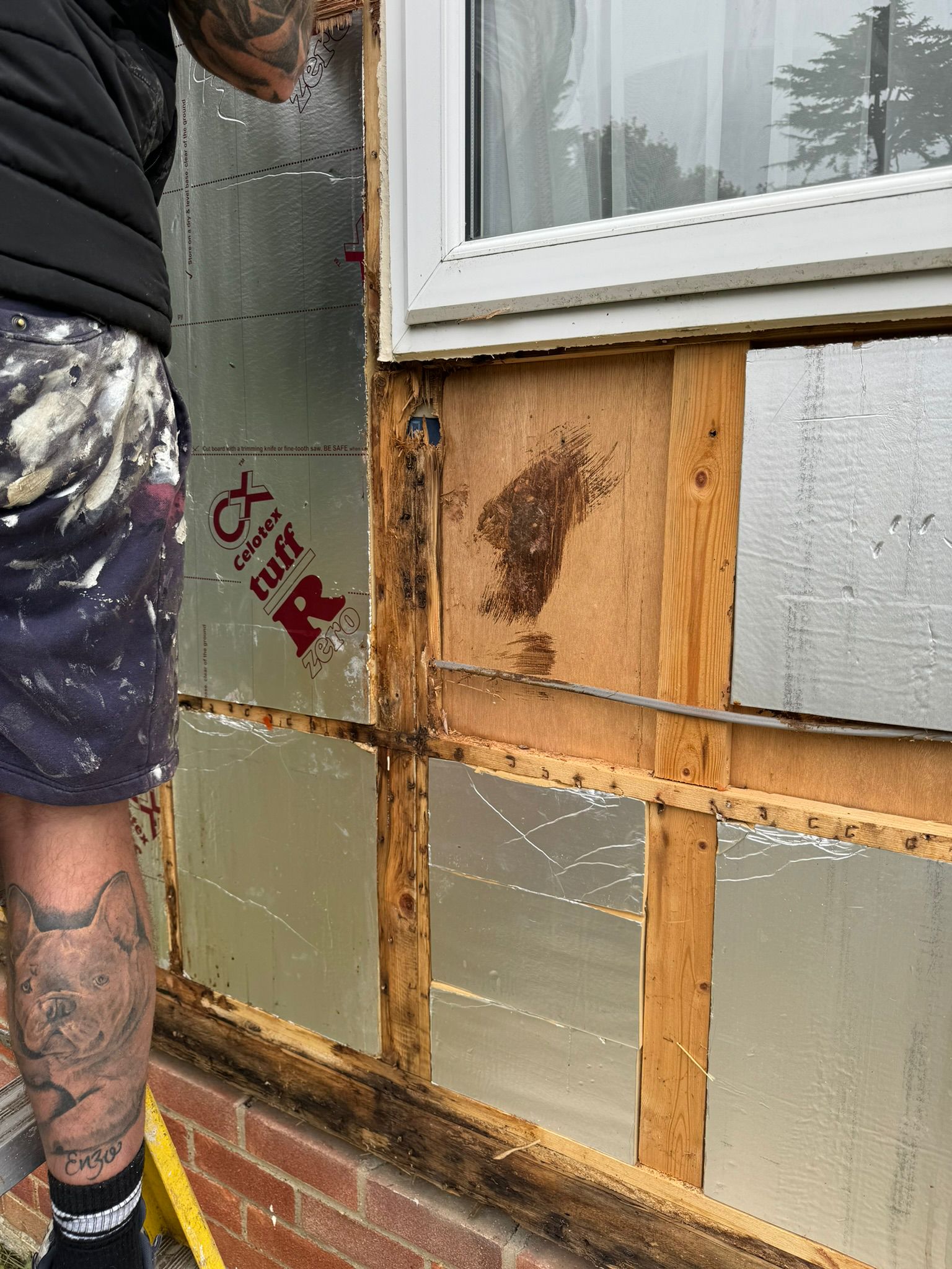 Worker fitting Celotex insulation boards between timber battens near park home window