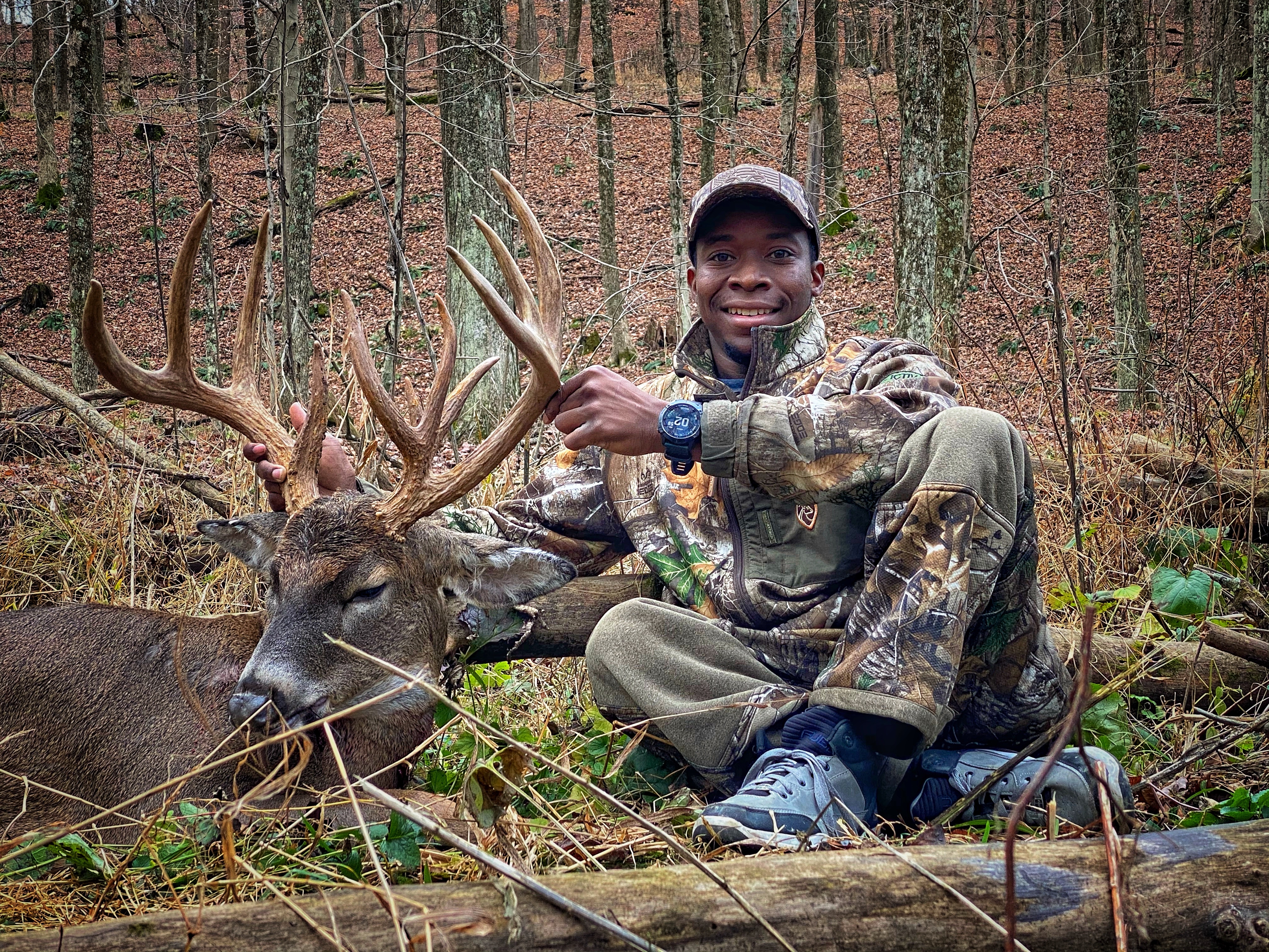 Joshua Carney with a trophy whitetail buck in the autumn hardwoods