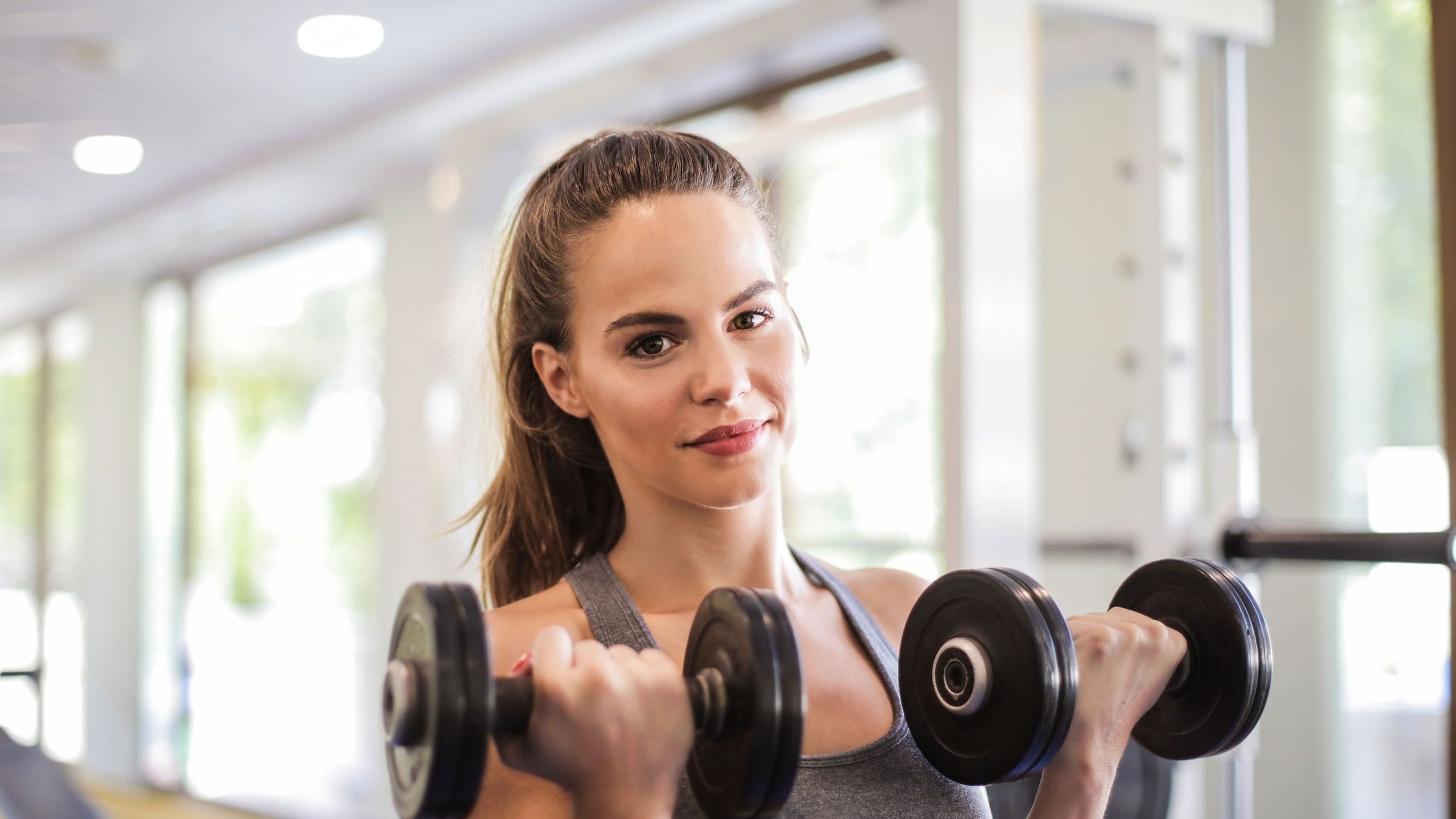 Vrouw traint met dumbbells in een lichte sportschool
