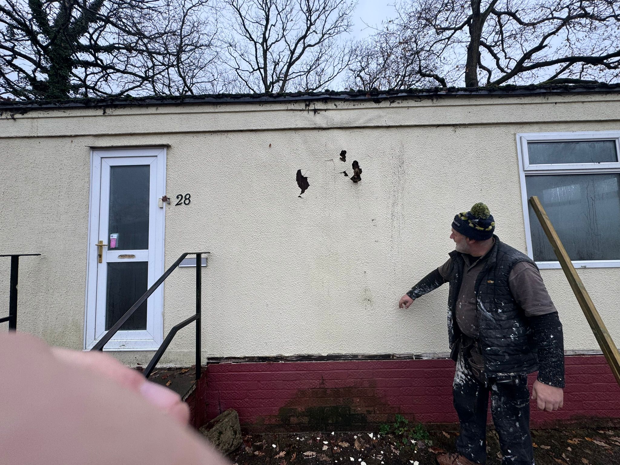Team member assessing wall damage on a park home exterior
