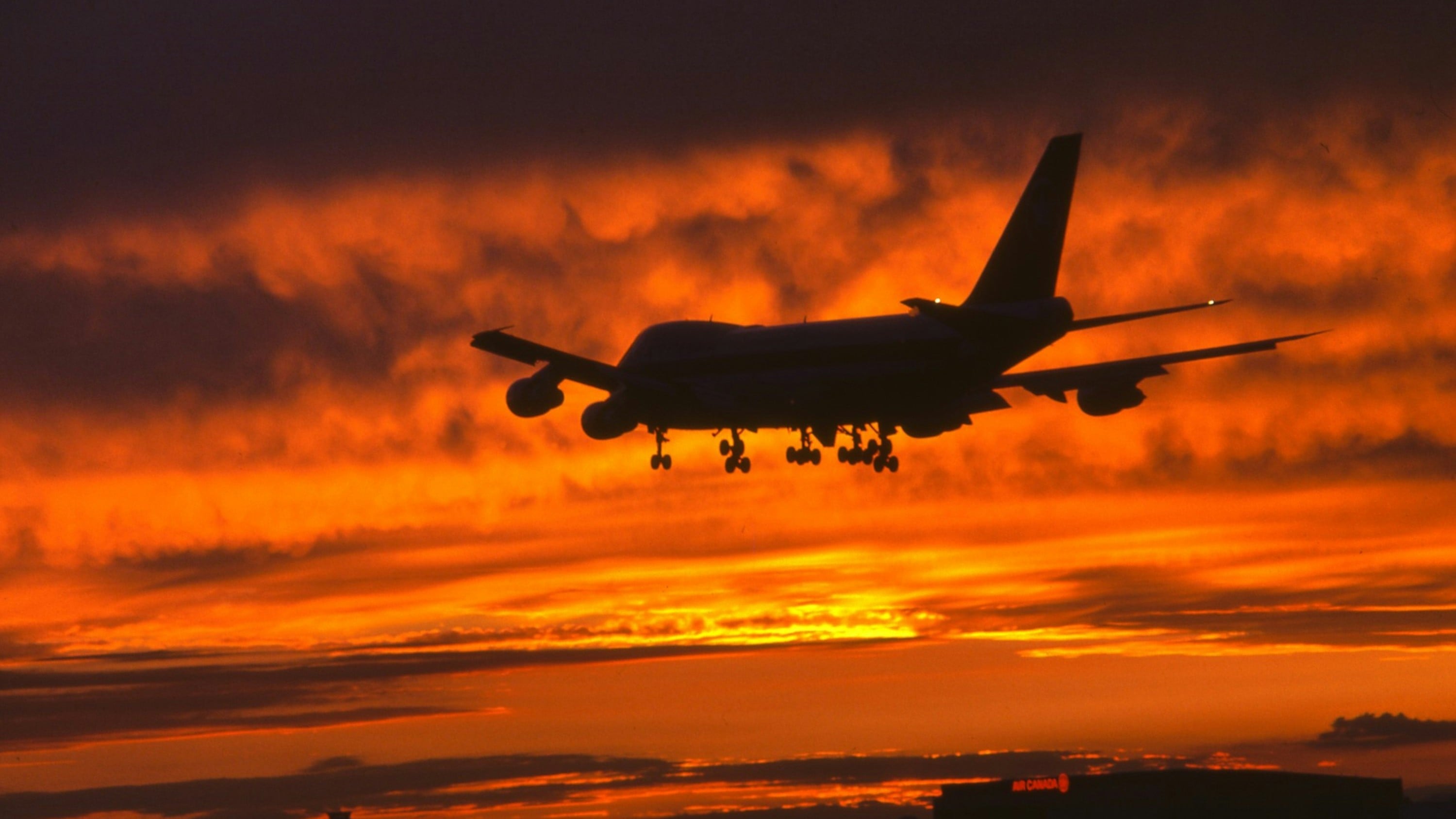 Airplane flying through sunset sky