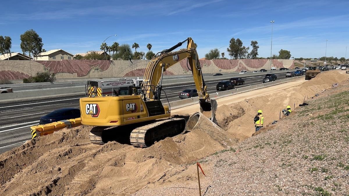 Excavator working on highway construction site with road corridor