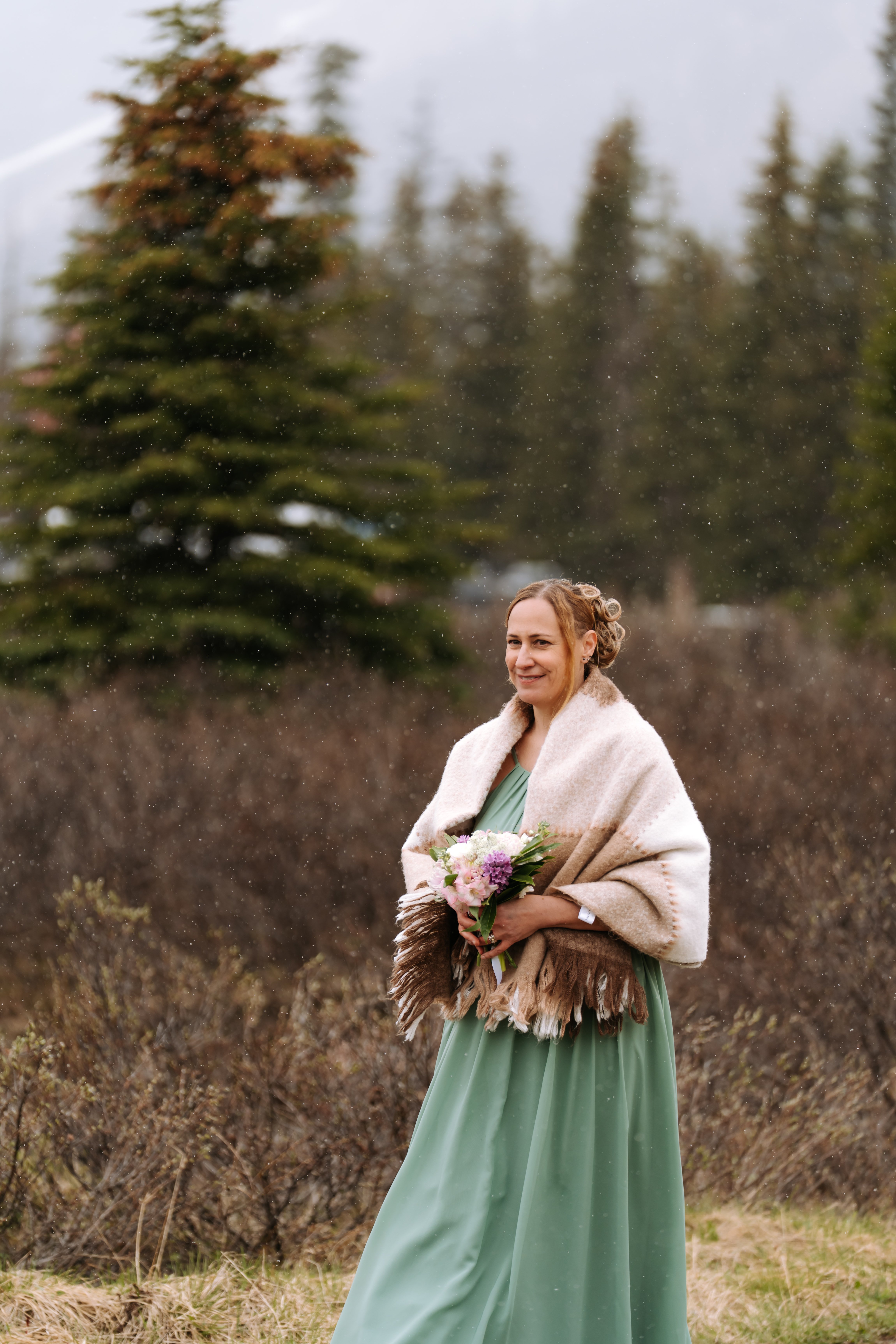 Bridesmaid in sage green holding a delicate mixed bouquet