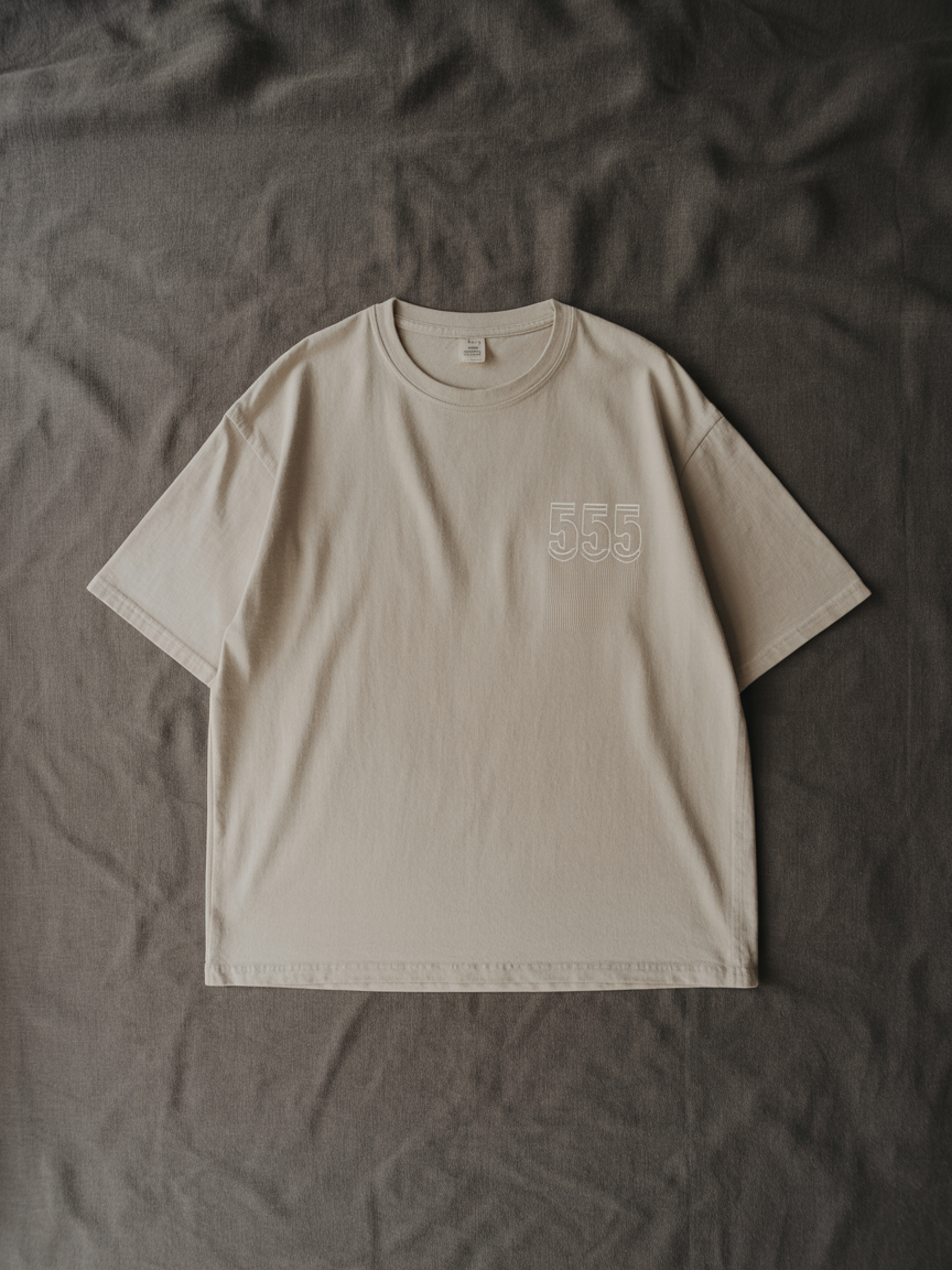 Pyramidion 555 Shift State Tee in bone, laid flat on charcoal linen.